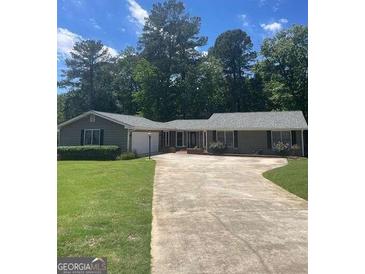 Charming single-story home featuring a long driveway and lush green lawn at 3705 Sandhill Se Dr, Conyers, GA 30094