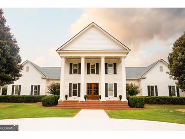 A grand two-story white home featuring stately columns, black shutters, and lush landscaping at 1875 Highway 142 E, Covington, GA 30014