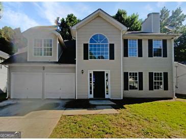 Two-story home with light siding, an arched window, a two-car garage, and a well-manicured front lawn at 4024 Waldrop Hills Dr, Decatur, GA 30034