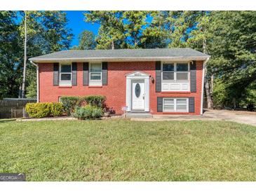 Charming brick home featuring well-maintained landscaping, black shutters, and a welcoming front entrance at 6671 Pelica Ct, Riverdale, GA 30274