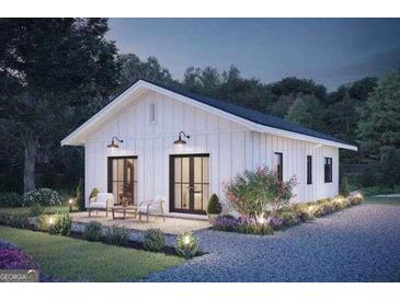 Charming exterior of white home with black trim, outdoor patio, and landscaped front yard at night at 17 Cheney St, East Point, GA 30344