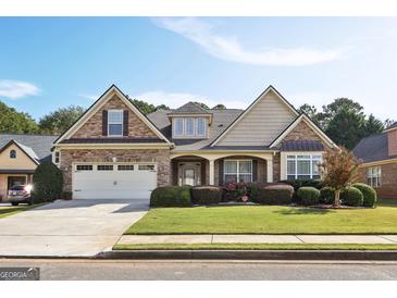 Two-story house with stone and beige siding, a three-car garage, and a landscaped lawn at 348 Relative Trl, Mcdonough, GA 30253