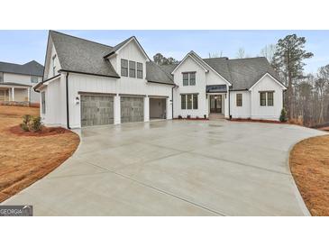 White farmhouse exterior with three-car garage and large driveway at 150 Dockside Dr # 382, Fayetteville, GA 30215