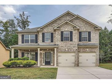 Charming two-story brick home with a well-manicured lawn, inviting front porch, and a two-car garage at 6624 Oak Hill Pass, Fairburn, GA 30213