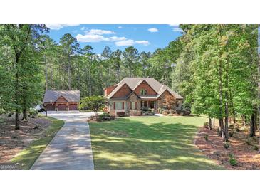 House exterior showcasing a stone and shingle two-story home with a three-car garage at 140 Haddock Pt, Brooks, GA 30205