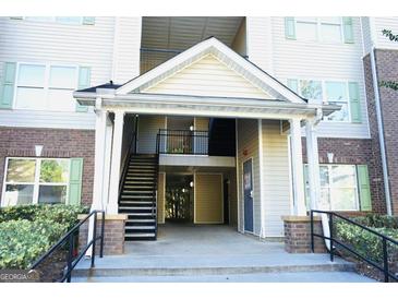 Inviting building entrance featuring covered stairs, a secure entry door, and lush surrounding landscaping at 12102 Fairington Ridge Cir # 12102, Lithonia, GA 30038