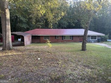Single story brick home featuring a metal roof, attached carport, and spacious front yard at 10108 Lakeview Sw Dr, Covington, GA 30014