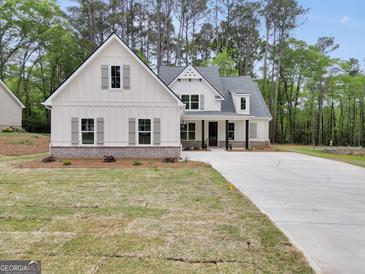 Charming white farmhouse-style home with a welcoming front porch, gray shutters and a freshly sodded lawn at 241 Ben Horton Dr, Mcdonough, GA 30253