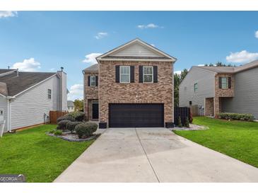Two-story brick home with a black garage door and landscaped lawn at 5602 Waverly Park, Atlanta, GA 30349