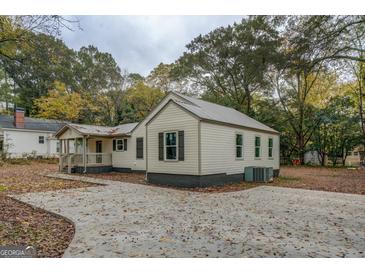 Charming bungalow featuring light siding, gray trim, metal roof, and a spacious driveway at 5122 Hillcrest Nw Dr, Covington, GA 30014