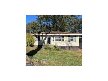 Modest single story home showing large front yard with mature trees and the need for some care at 1511 Walker Ave, College Park, GA 30337
