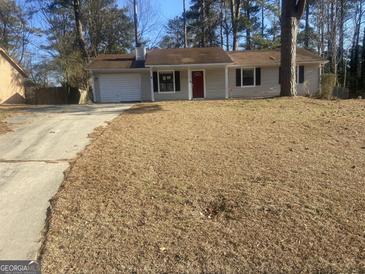 Ranch-style home with attached garage and red front door at 9051 Homewood Dr, Riverdale, GA 30274