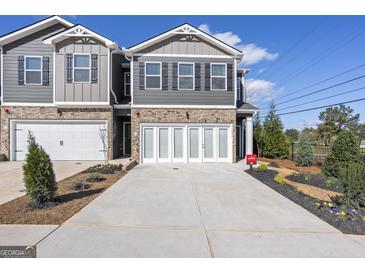 View of newly built townhomes with brick and gray siding, manicured lawns, and two-car garages at 11553 Kimberly Way # 18, Hampton, GA 30228