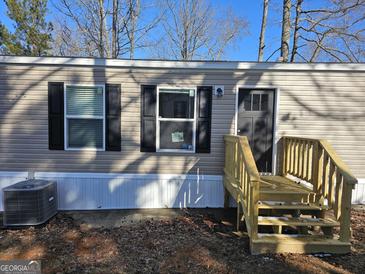 Tan mobile home with black door, wooden steps, and air conditioning unit at 1915 Cardell Rd # C15, Austell, GA 30168