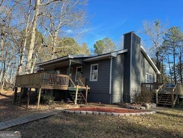 Charming home with a wooden deck and a landscaped yard surrounded by mature trees at 2020 Moore Rd, Moreland, GA 30259
