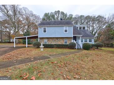 Charming two-story home with stone accents, a carport, and mature trees in a landscaped yard at 3954 Swathmore Ln, Duluth, GA 30096