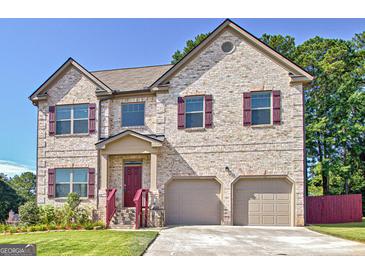 Two-story brick house with a red door, two-car garage, and landscaped yard at 633 Mill Creek Trl, Jonesboro, GA 30238