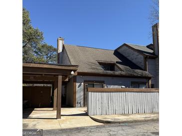 Two-story home featuring aged siding, a carport, and a low fence at 97 Willowick Dr, Lithonia, GA 30038