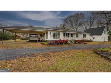 Charming single story home with large carport, landscaped front yard, and white siding at 12178 Brown Bridge Rd, Covington, GA 30016