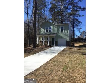 Two-story house with green siding, white columns, and a driveway at 9168 Carr Cir, Covington, GA 30014
