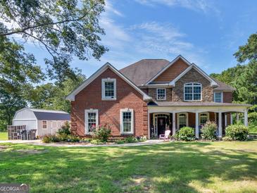 Brick house with stone accents, a large front porch, and landscaping at 10 Toscanno Dr, Covington, GA 30014