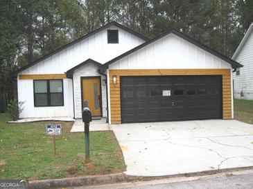 Newly constructed home with a modern farmhouse exterior, featuring a two-car garage and attractive landscaping at 4490 Latchwood Dr, Lithonia, GA 30038