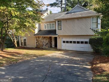 Two-story house with beige siding, stone accents, and a two-car garage at 4767 Glenwhite Dr, Duluth, GA 30096