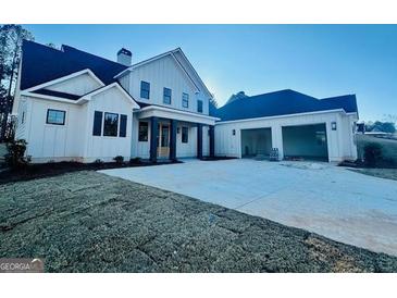 Two-story farmhouse features white siding, a large front porch, and a detached garage at 145 Dockside Dr # 396, Fayetteville, GA 30215