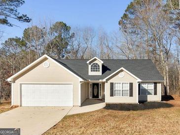 Beige house with two-car garage and landscaping at 135 Kimbell Farm Dr, Locust Grove, GA 30248