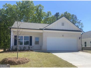 Charming single-story home with a white brick facade, manicured lawn, and attached two-car garage at 1479 Trellis Court (Lot 3), Hampton, GA 30228