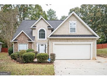 Two-story house with stone accents and a two-car garage at 308 Royal Crescent Way, Stockbridge, GA 30281