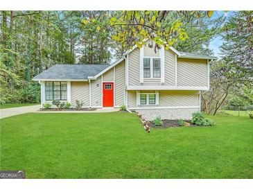 Two-story house with red door, light beige siding, and green lawn at 3951 Wabash Ln, Ellenwood, GA 30294