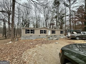 Tan single-wide mobile home with black shutters, surrounded by trees at 58 Pinewood Dr, Carrollton, GA 30116