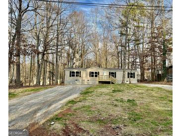 Charming single-story home with neutral siding, black shutters and inviting front porch situated on a treed lot at 58 Pinewood Dr, Carrollton, GA 30116