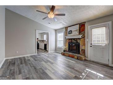 Spacious living room featuring a stone fireplace and view into the kitchen at 5495 Reynolds Rd, Morrow, GA 30260