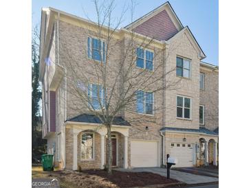 Brick three-story townhome with two-car garage and landscaping at 4879 Pinnacle Dr, Stone Mountain, GA 30088