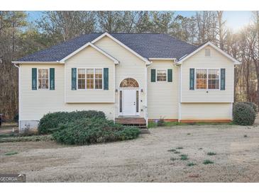 House exterior featuring a yellow vinyl-sided house, a gray roof, and a well-maintained lawn at 718 Grove Pointe Cir, Locust Grove, GA 30248