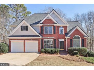 Beautiful two-story brick home with a two car garage, black shutters, and a well-maintained lawn at 5034 Hickory Hills Dr, Woodstock, GA 30188
