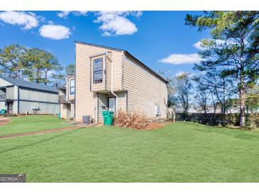 Tan two-story townhouse with green lawn and mature trees at 6036 Regent Mnr, Lithonia, GA 30058