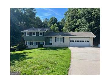Charming split-level home featuring a two-car garage, well-manicured lawn, and a tree-lined backdrop at 6667 Ridge Moore Dr, Peachtree Corners, GA 30360