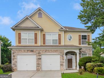 Two-story house with three-car garage, stone accents, and landscaping at 7356 Blue Jay Way, Union City, GA 30291