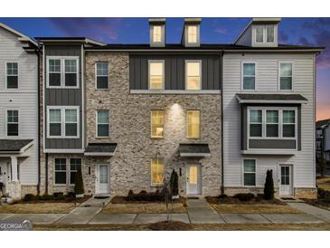 Three-story townhome with gray and white exterior, brick accents, and walkway at 295 Cobalt Dr, Fayetteville, GA 30214