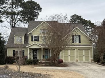 Two-story house with three-car garage, light beige siding, and a nicely landscaped yard at 5025 Hidden Ct, Cumming, GA 30040