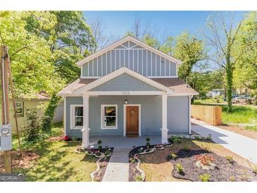 Charming blue two-story home featuring a landscaped yard and a welcoming front porch at 1302 Ladd St, Atlanta, GA 30310