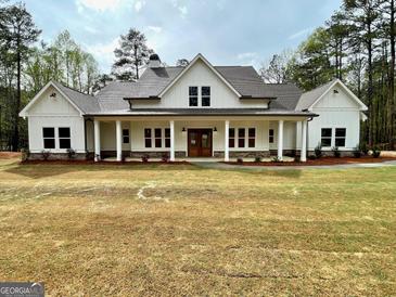 Inviting two-story modern farmhouse with a welcoming front porch and a well-manicured lawn at 4619 Parkwood Rd, Social Circle, GA 30025