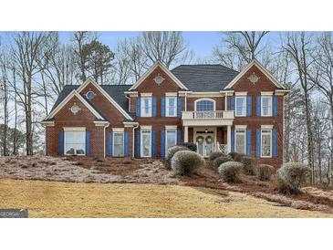 Beautiful two-story red brick home featuring blue shutters and manicured front yard landscaping at 230 Hedgewick Way, Tyrone, GA 30290