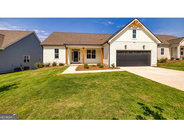 White farmhouse exterior with a large yard and two-car garage at 69 Oakhurst Trl, Sharpsburg, GA 30277