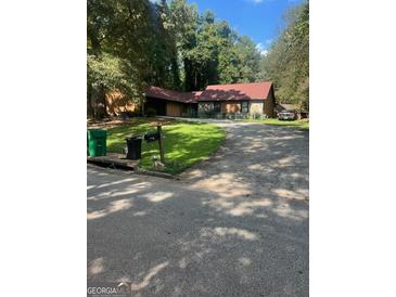 Ranch style home with red roof, nestled in a wooded area at 1430 Stoneleigh Hill Rd, Lithonia, GA 30058
