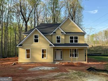 New construction home with yellow siding, black roof, and welcoming front porch at 142 Asa Moseley Rd, Mcdonough, GA 30252