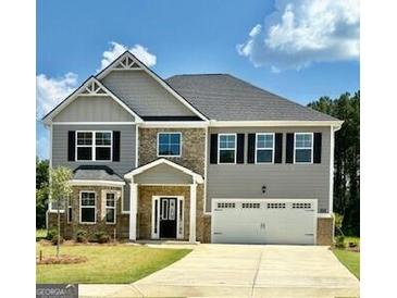 Charming two-story home with a manicured lawn, stone accents, and a two-car garage at 13232 Tolstoy Drive, Covington, GA 30014